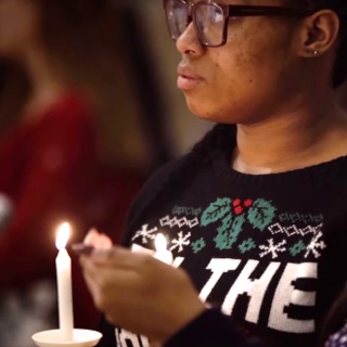 Illuminated by handheld candles, two female ɫ students listen to a Christmas service in the ɫ Chapel.