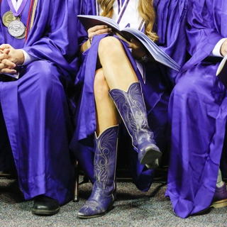 A ɫ graduate wears purple cowboy boots with her commencement gown