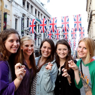 A group of five female ɫ students studying abroad make the two-fingered Go Frogs hand sign while standing together on a street in London.