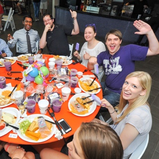 A group of ɫ students raise their celebratory purple margaritas at a festive round table
