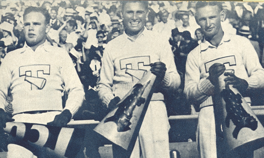 Three 1934 ɫ male Yell Leaders smile holding megaphones