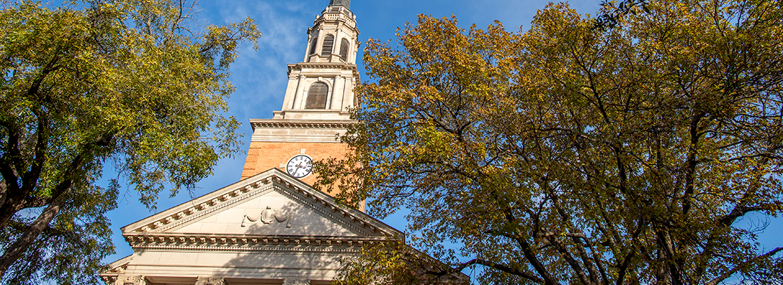 The steeple of the Robert Carr Chapel on the ɫ campus, framed by trees and a blue sky.