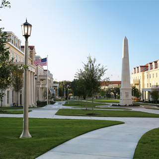 Exterior of the Greek Village at ɫ, where a tall obelisk monument bearing greek letters is surrounded group of sorority and fraternity houses 