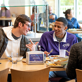Two male ɫ students share a laugh over lunch at the campus main dining hall