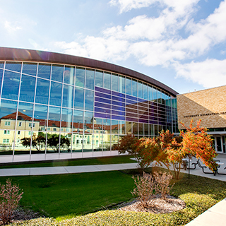 An exterior of the ɫ Campus Rec center; other campus buildings are reflected in its shiny surface.