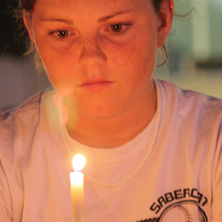 Close up of female ɫ student looking thoughtful as she holds a candle before her face.